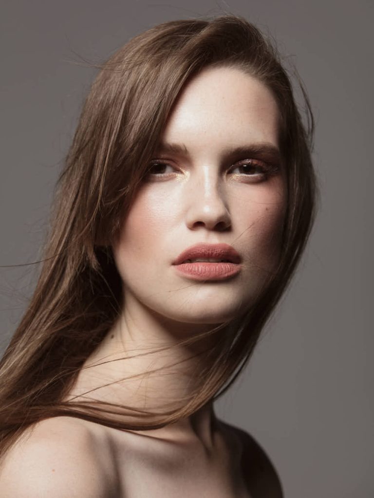 Retrato de mujer con maquillaje minimalista y collar de perlas, ejemplo de fotografía belleza minimalista, elegante y natural.